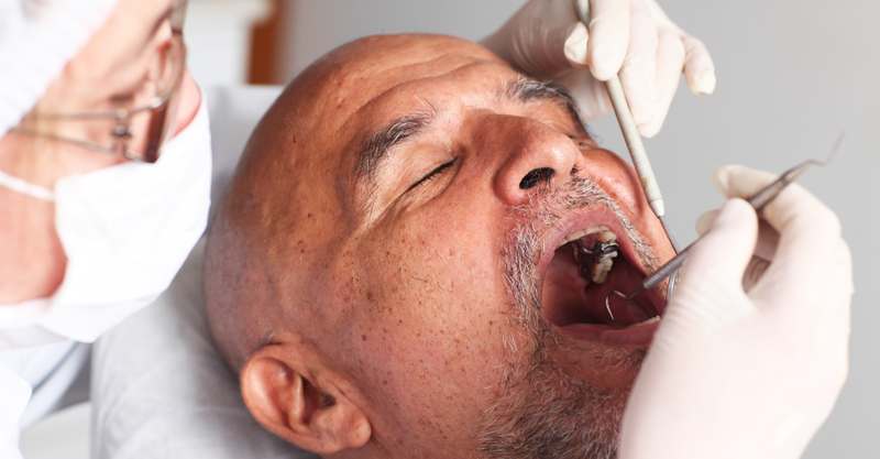 Elderly man having an oral hygiene check-up at dentist.