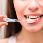 Smiling woman's mouth with toothbrush ready to be used.